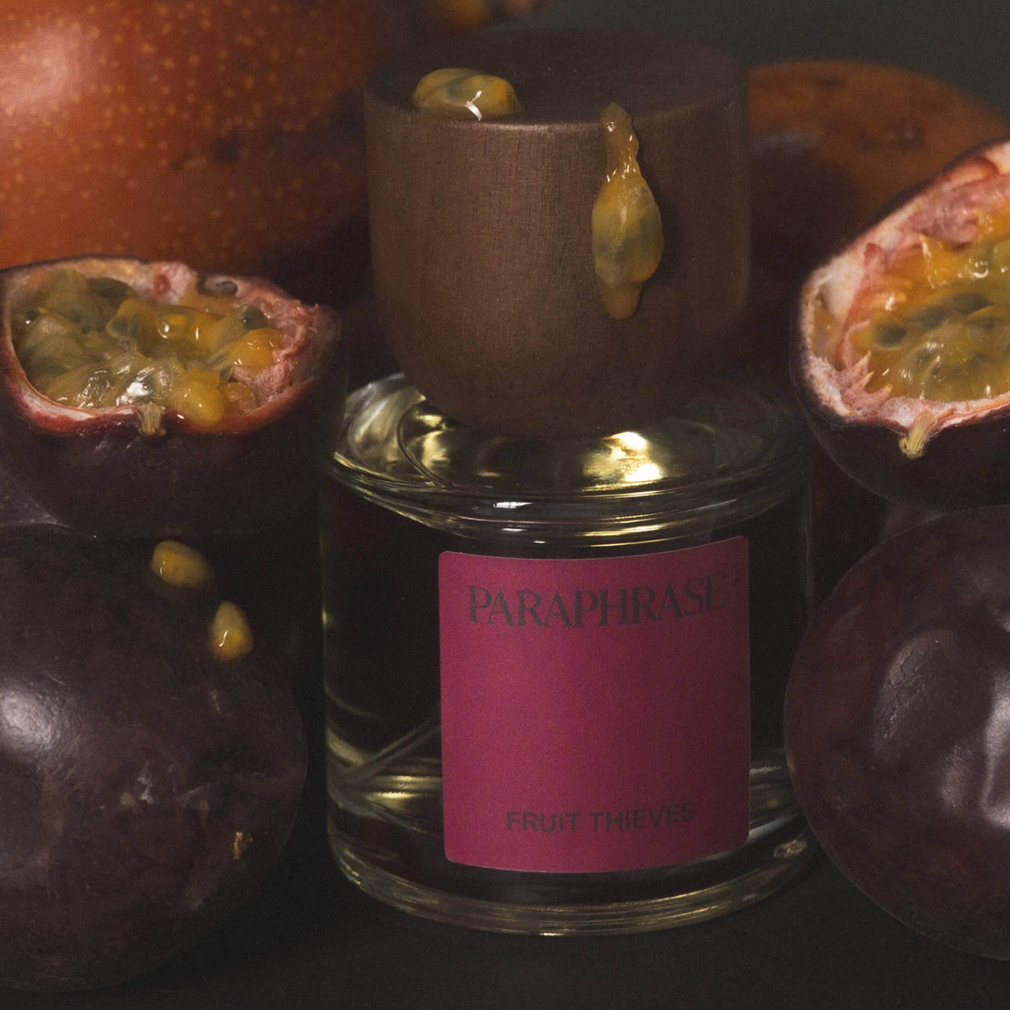 Fruit Thieves perfume bottle with passion fruit and dripping juice on dark background