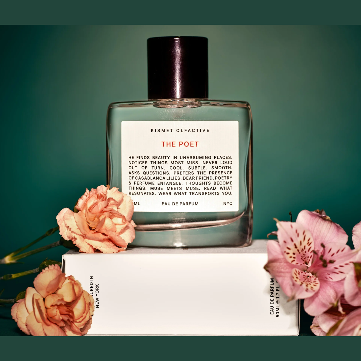 The Poet perfume bottle by Kismet Olfactive styled with peach carnations on teal background