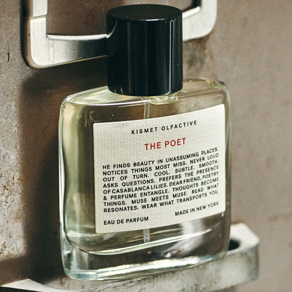 Close-up of Kismet Olfactive The Poet fragrance bottle on weathered metallic surface