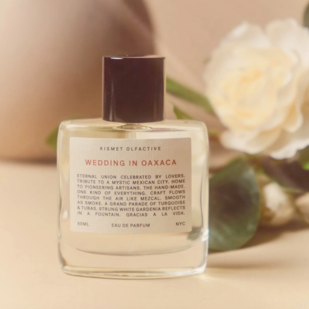 Kismet Olfactive Wedding in Oaxaca Eau de Parfum bottle with coconut and tuberose notes on floral background