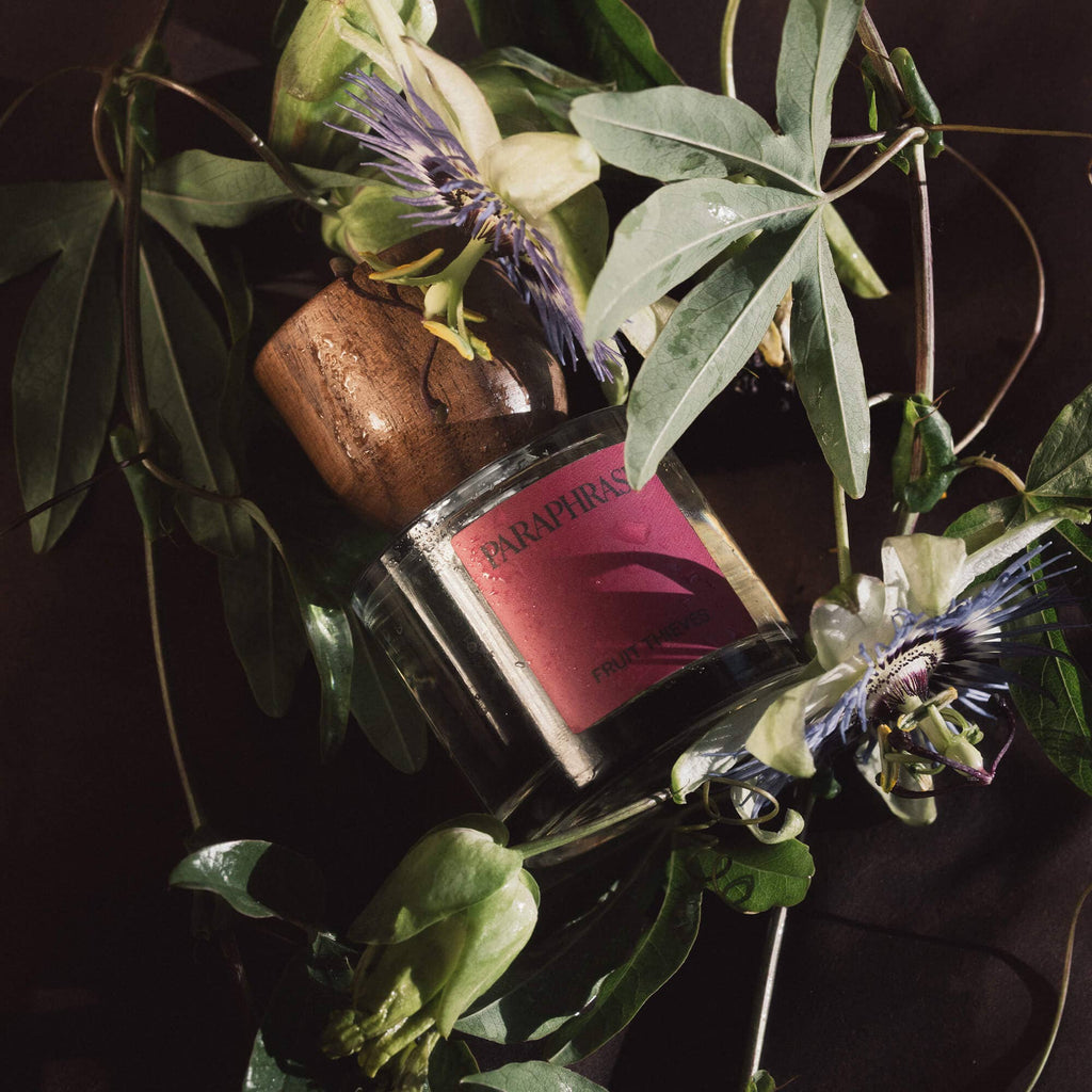 Paraphrase Fruit Thieves perfume nestled among open passionflowers and green leaves