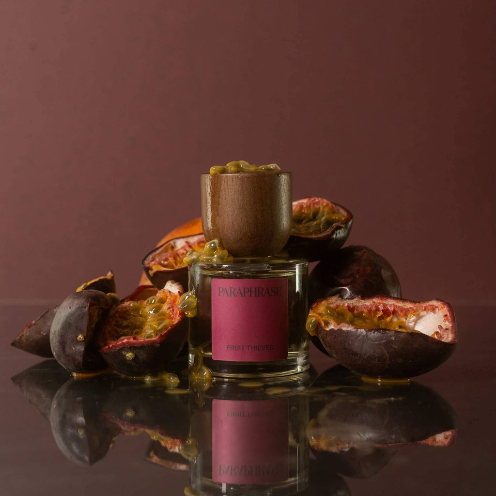 Fruit Thieves Eau de Parfum standing with halved passion fruits and dripping juice