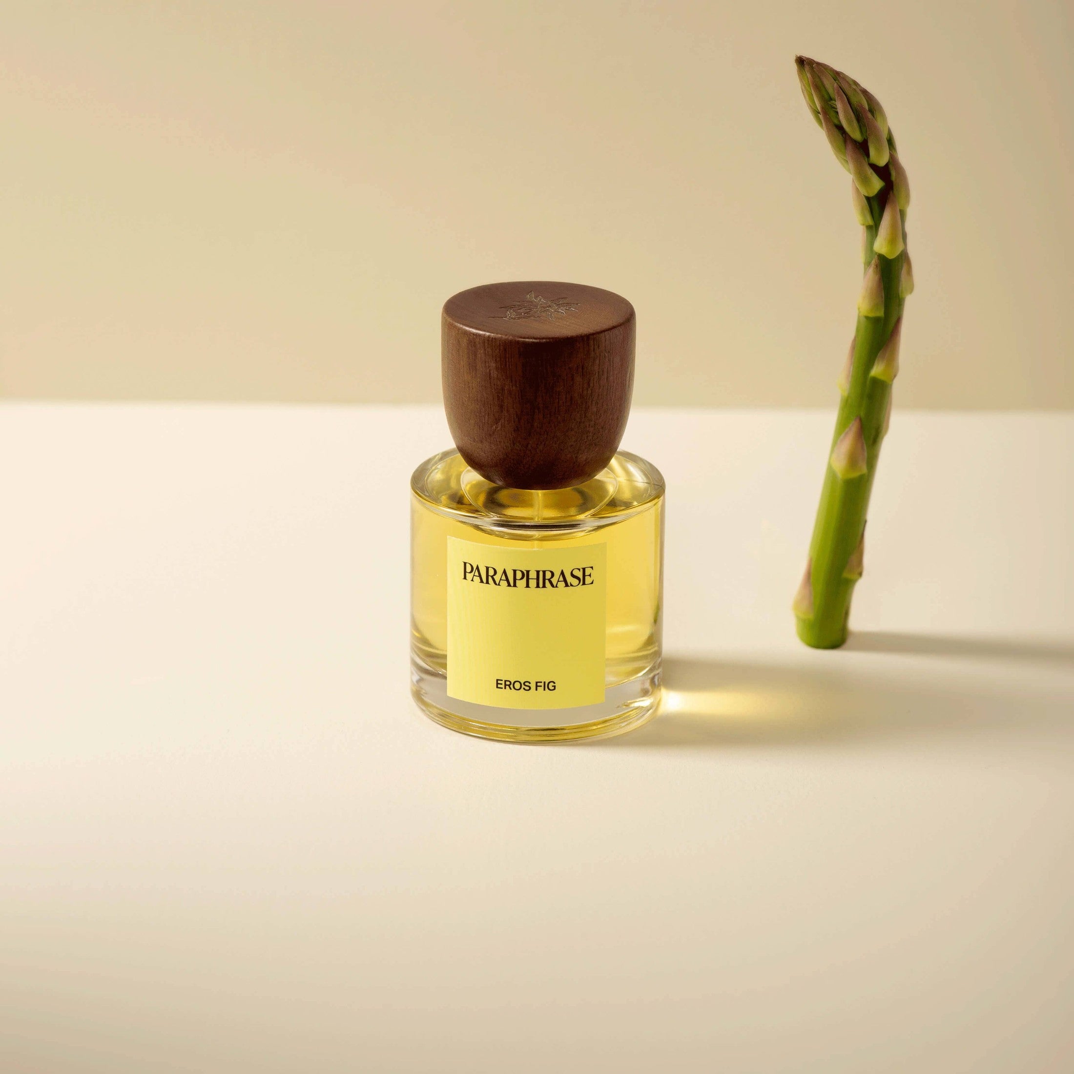 Paraphrase Eros Fig perfume bottle with asparagus spear on off-white surface