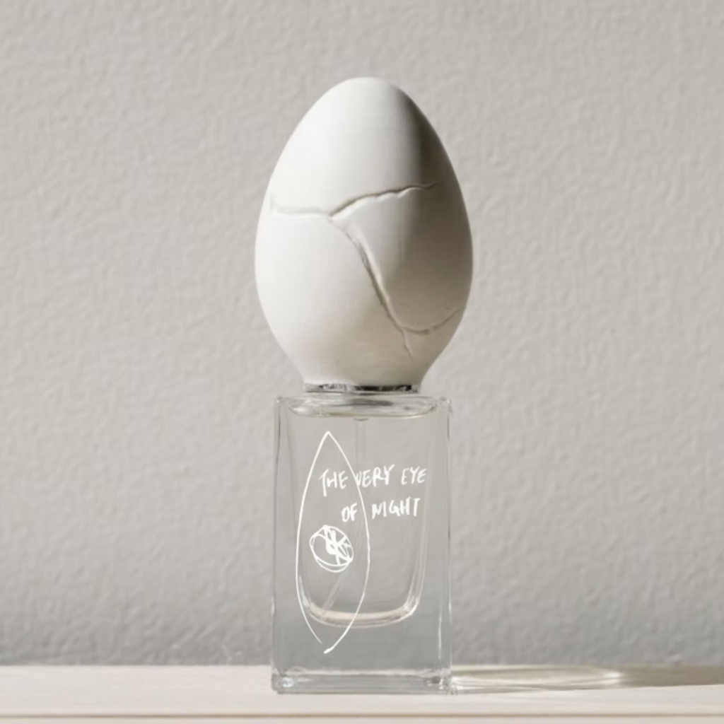 Perfume Who - the very eye of night. Egg-shaped bottle with a cracked top on a light gray background